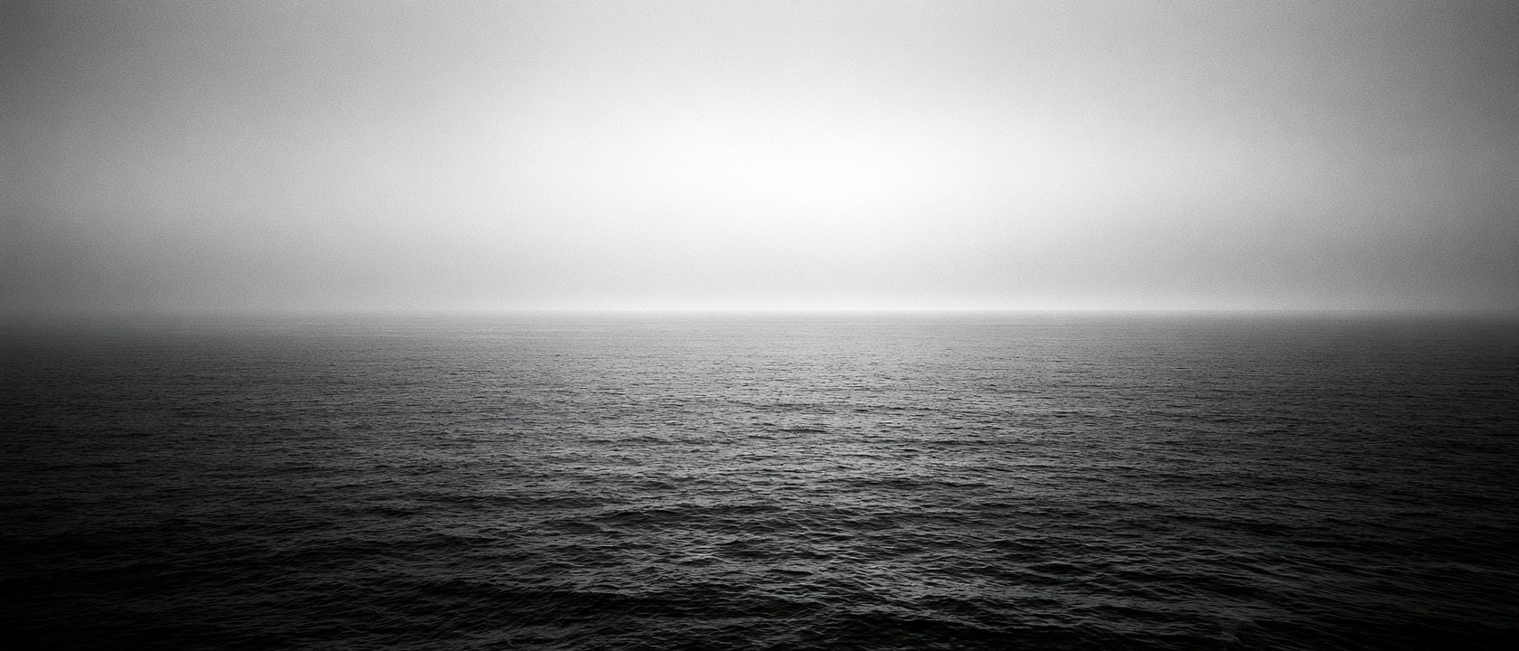 Ligne d'horizon entre ciel couvert et mer sombre